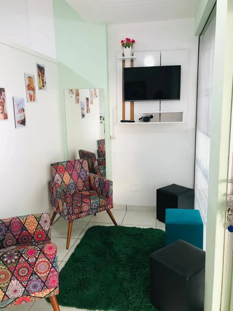 Recepção com poltronas estampadas, puffs verdes e tapete